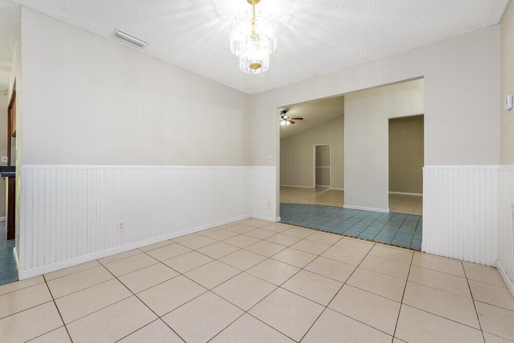 A dining room features beige tile floors, white wainscoting, and a crystal chandelier — WELLINGTON, FL