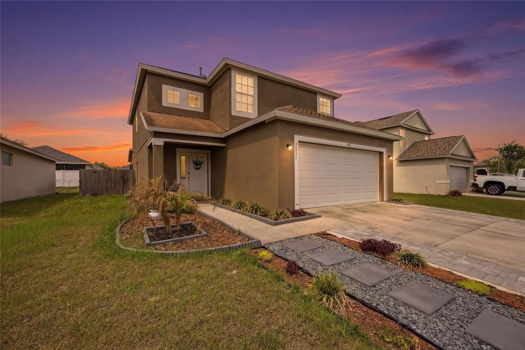 A two-story house with a tan exterior, a two-car garage, and a landscaped front yard — 24927 PORTOFINO DRIVE, LUTZ, FL