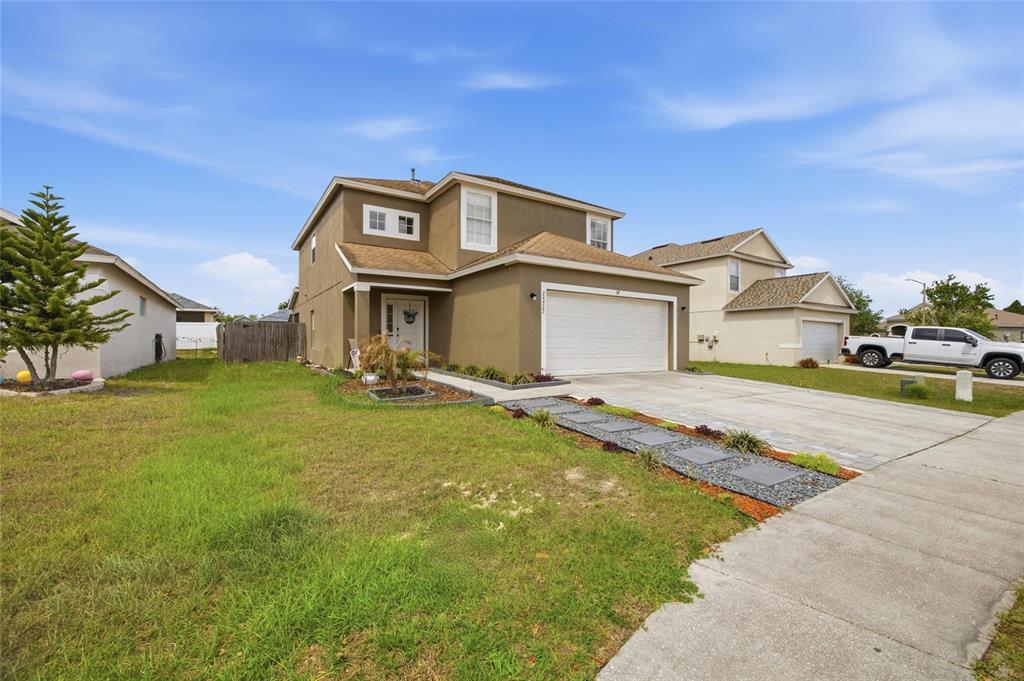 A two-story tan house with a two-car garage and a paved walkway in front — 24927 PORTOFINO DRIVE, LUTZ, FL