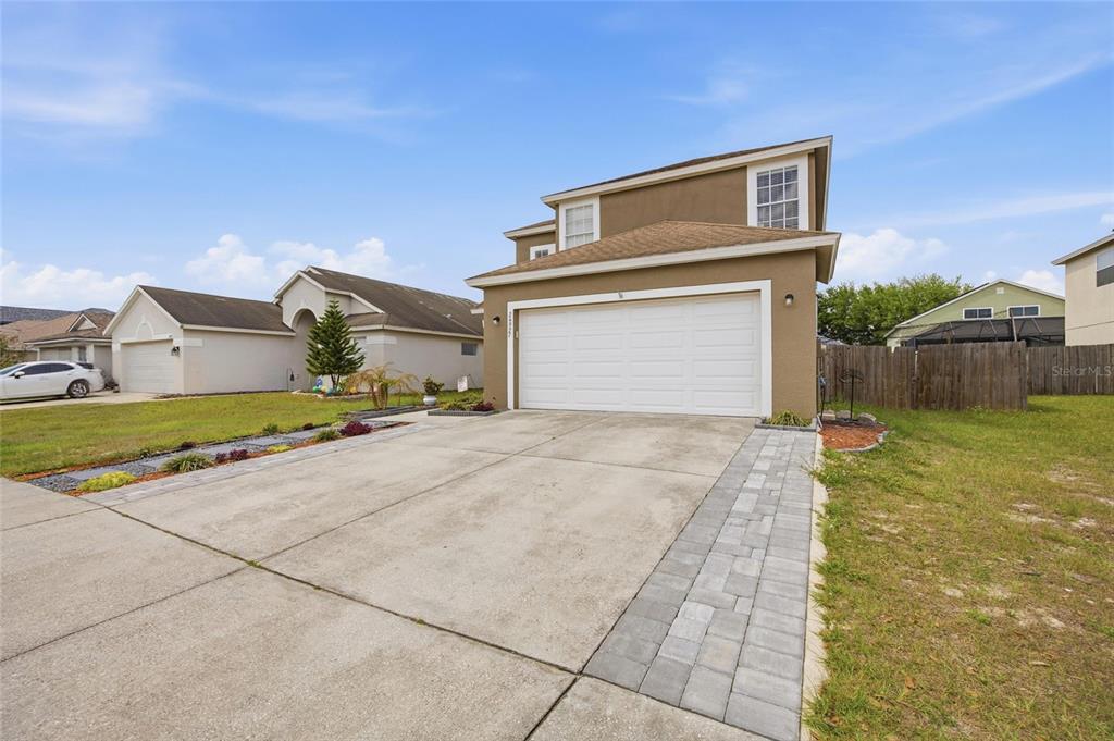 A two-story tan house with a white garage door and a paved driveway — 24927 PORTOFINO DRIVE, LUTZ, FL