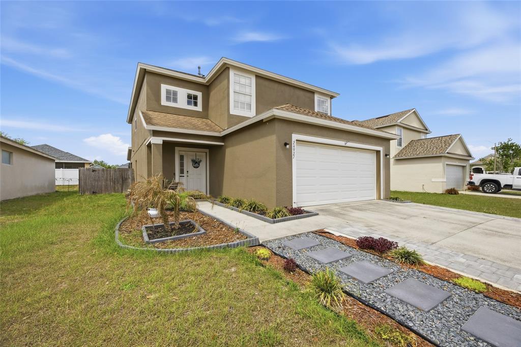A two-story house with a tan stucco exterior, a white garage door, and a walkway — 24927 PORTOFINO DRIVE, LUTZ, FL