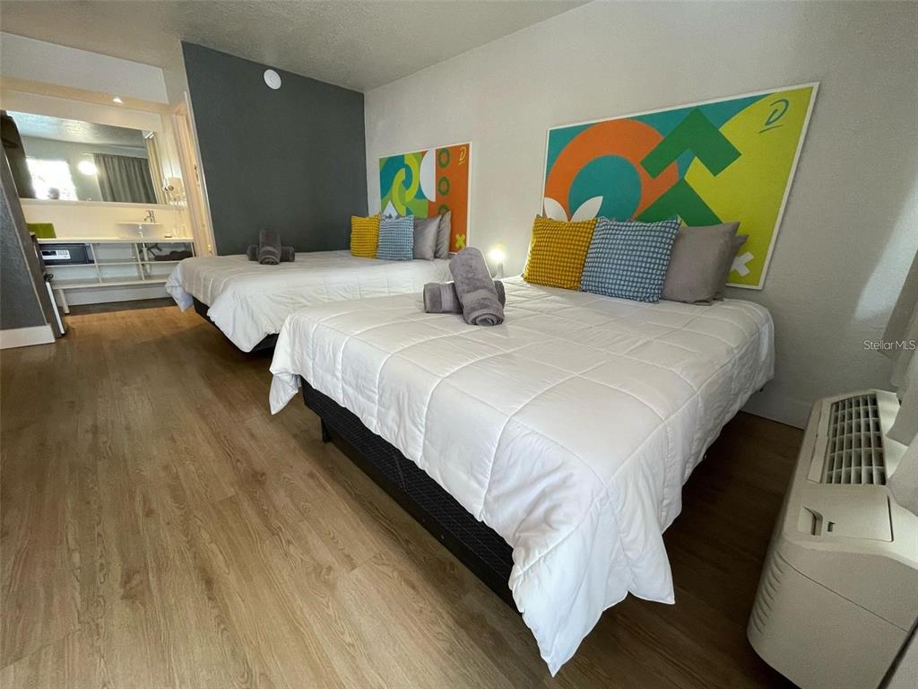 A hotel room features two beds with white comforters, colorful headboard art, and wood-look flooring — 5367 W IRLO BRONSON MEM HWY UNIT 1-203, KISSIMMEE, FL
