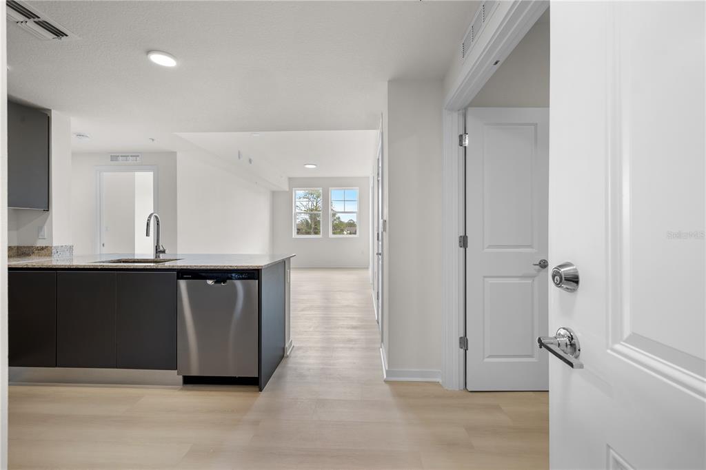 A kitchen island with a stainless steel dishwasher sits in an open-concept living area — 5579 MILLENIA PARK BOULEVARD UNIT 323, ORLANDO, FL