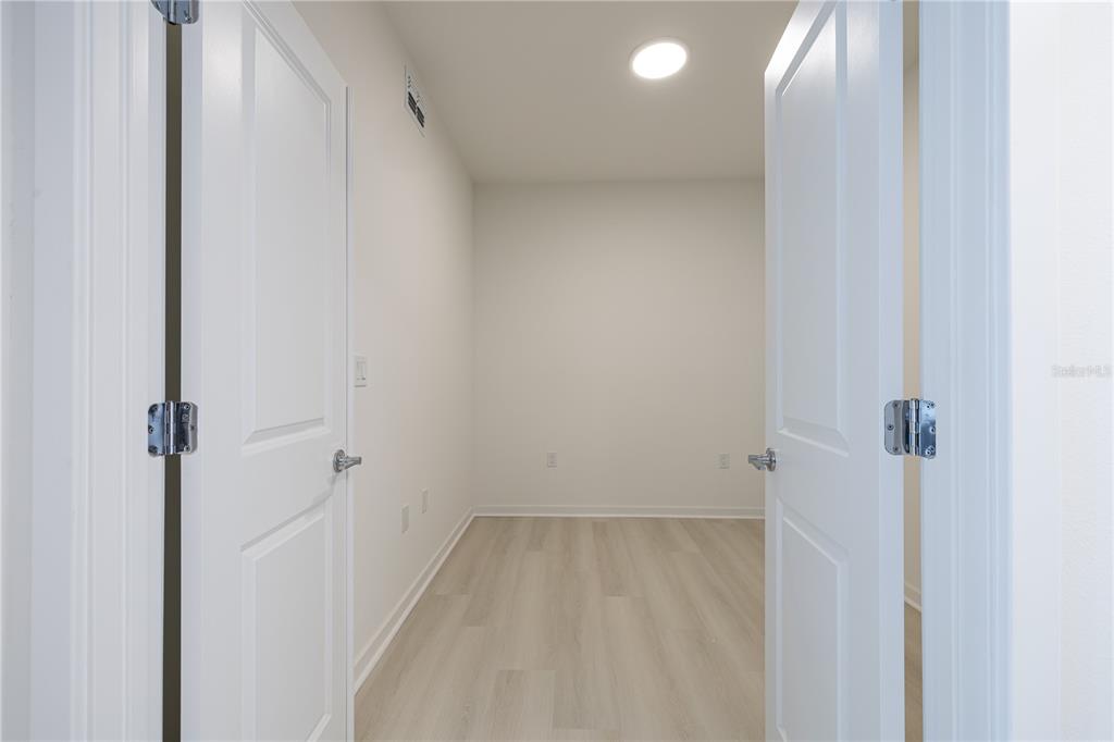 A small room with light wood-look flooring and white walls viewed through double doors — 5579 MILLENIA PARK BOULEVARD UNIT 323, ORLANDO, FL
