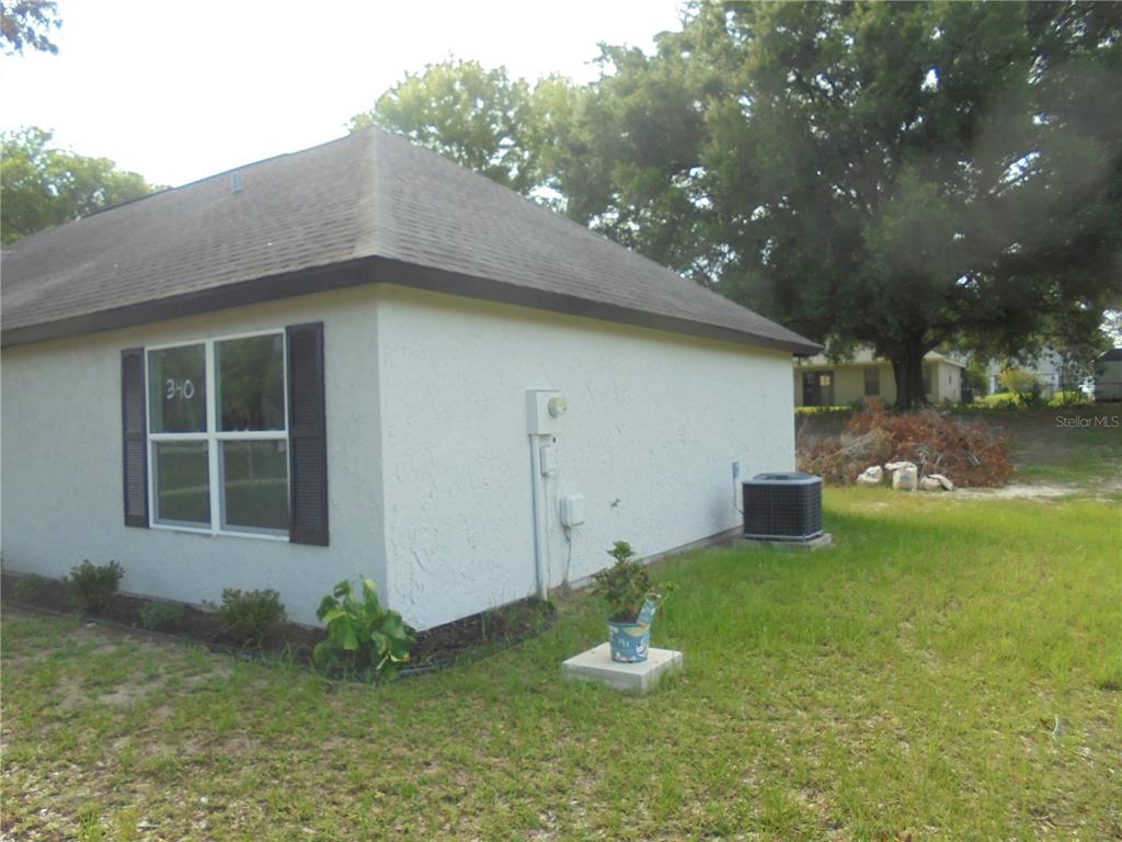 The exterior of a white stucco house features a window, an air conditioning unit, and landscaping — 340 EMERALD ROAD, OCALA, FL
