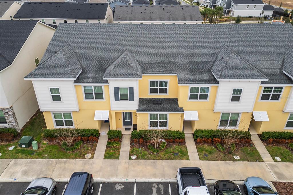 An aerial view of a yellow multi-unit townhouse building with gray shingled roofs — 2309 DISTANT SUN TRAIL, KISSIMMEE, FL