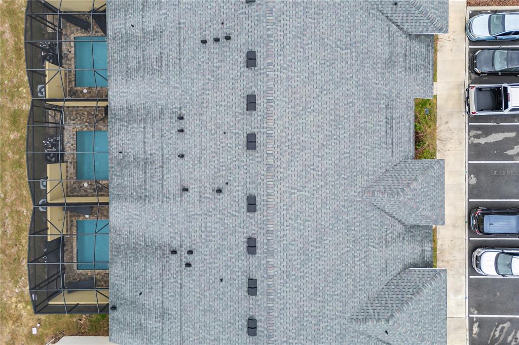 An aerial view shows a shingled roof, screened-in pools, and a parking lot with cars — 2309 DISTANT SUN TRAIL, KISSIMMEE, FL