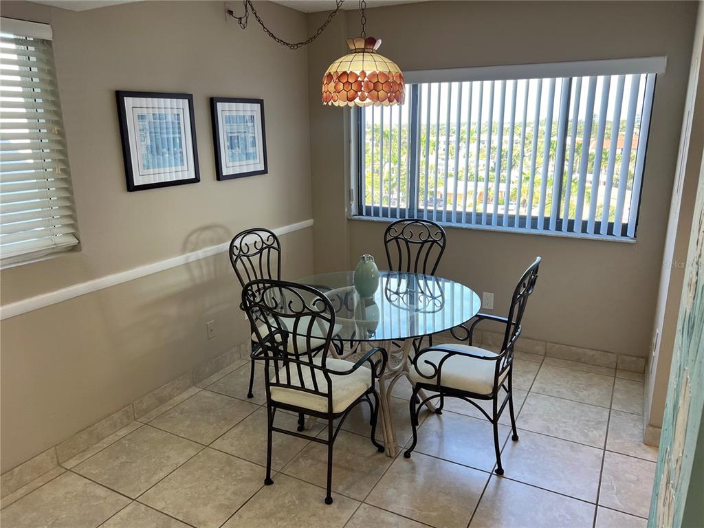 A dining area features a glass-topped table, four metal chairs, and a stained-glass pendant light — 1001 POINT OF ROCKS ROAD UNIT 608, SARASOTA, FL