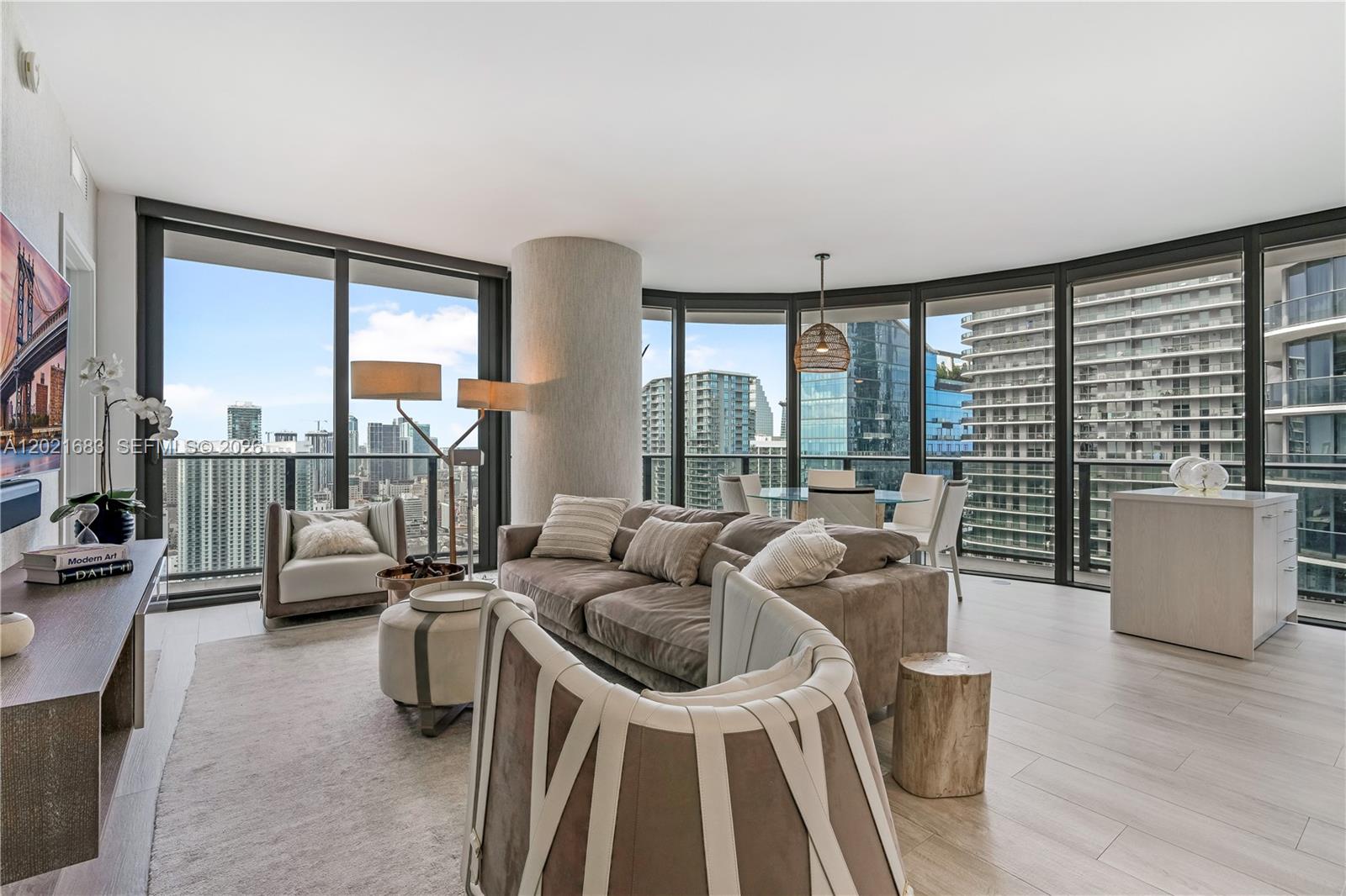 A modern living room with floor-to-ceiling windows, a brown sofa, and city skyline views — 55 SW 9th St # 4001, Miami FL 33130, MIAMI, FL