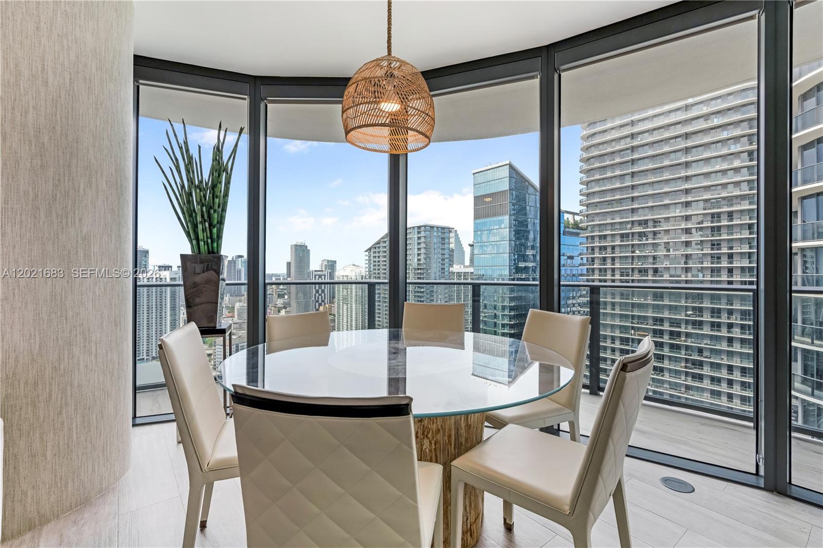 A dining area features a glass-topped table, beige chairs, and floor-to-ceiling windows with city views — 55 SW 9th St # 4001, Miami FL 33130, MIAMI, FL