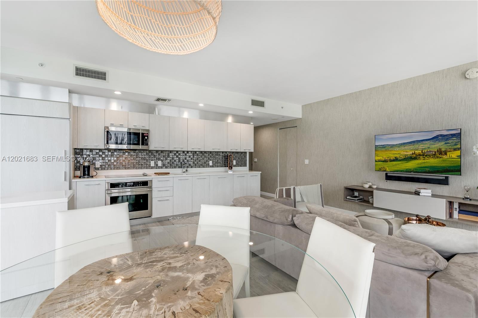 A modern open-concept living area features a kitchen with light cabinetry and a dining table — 55 SW 9th St # 4001, Miami FL 33130, MIAMI, FL