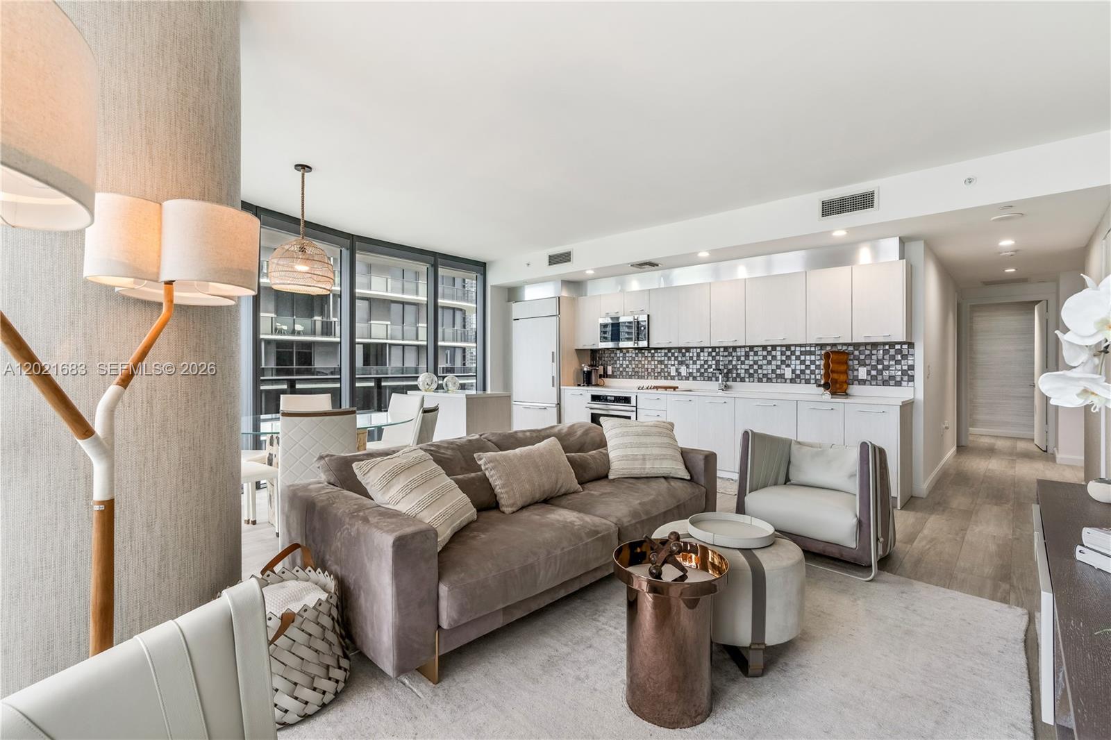 A modern open-concept living room and kitchen featuring neutral tones and floor-to-ceiling windows — 55 SW 9th St # 4001, Miami FL 33130, MIAMI, FL