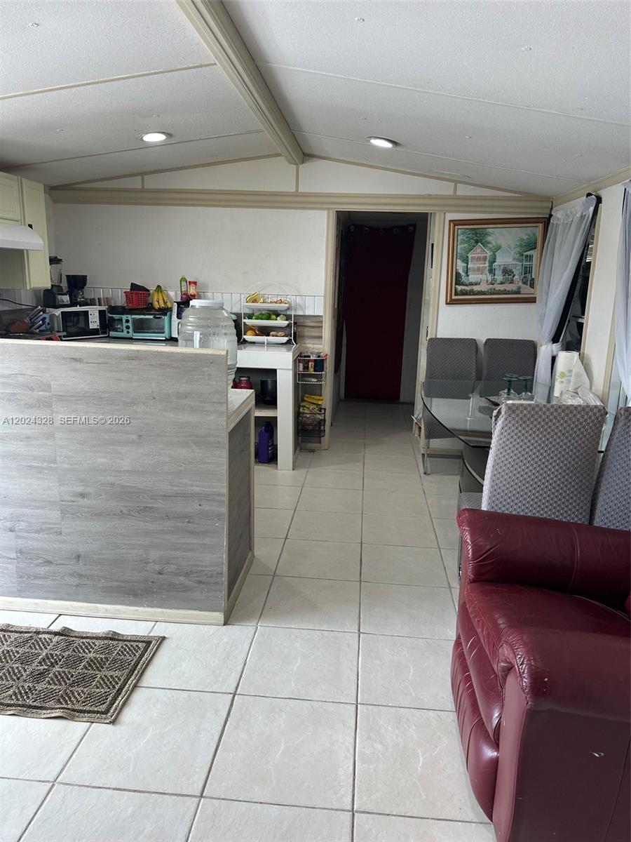A kitchen with a grey wood-look island, tiled floors, and an adjacent dining area — 625 N QUEBRADA, Clewiston FL 33440, CLEWISTON, FL