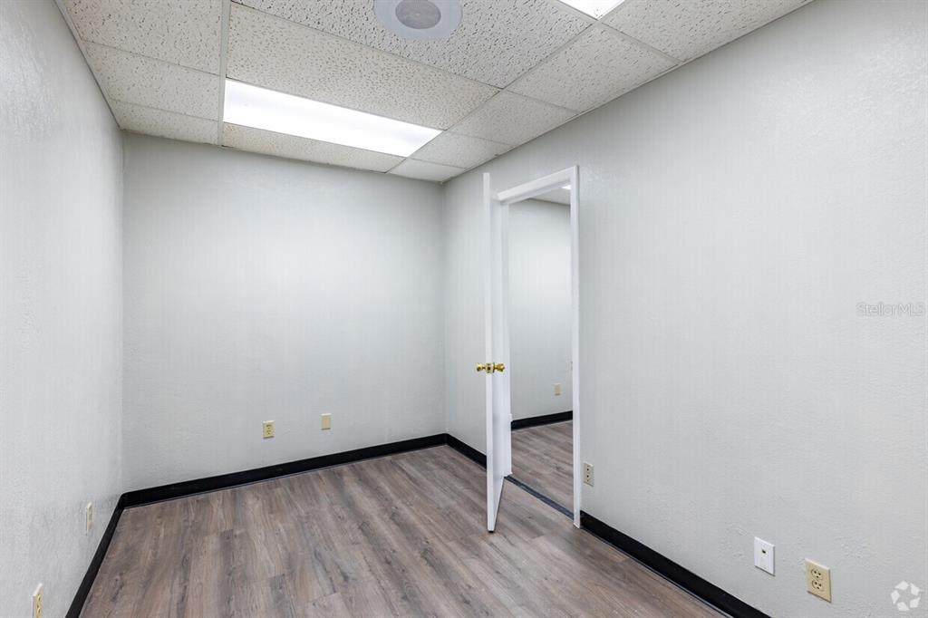 An empty office room features light gray walls, wood-look flooring, and a drop ceiling — 5623 US-19 N HIGHWAY, NEW PORT RICHEY, FL