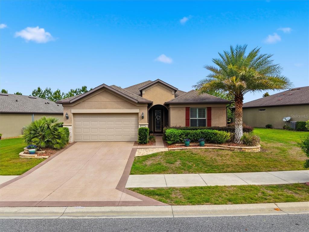 A single-story tan stucco house with a two-car garage and a front palm tree — 9641 SW 76TH PLACE, OCALA, FL