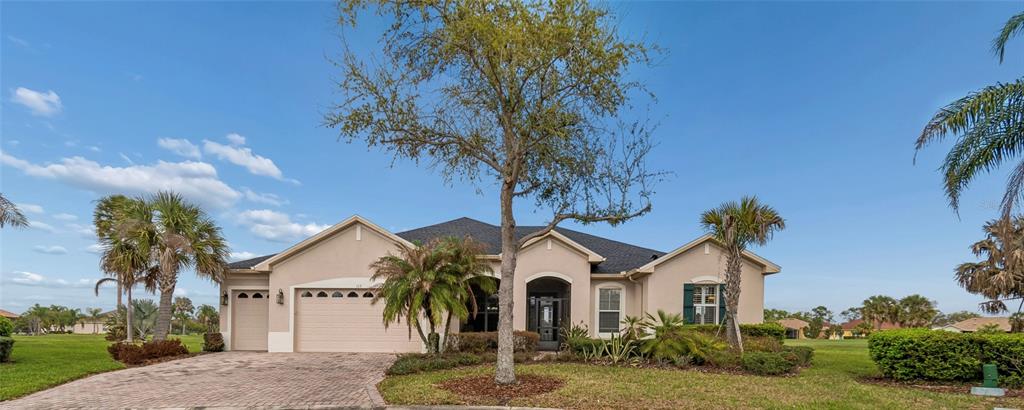 A single-story house with a beige stucco exterior, a paved driveway, and a large tree — 113 TIVOLI TRACE CT, POINCIANA, FL