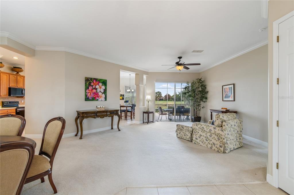 A carpeted living room features a floral armchair, a console table, and a sliding glass door — 113 TIVOLI TRACE CT, POINCIANA, FL