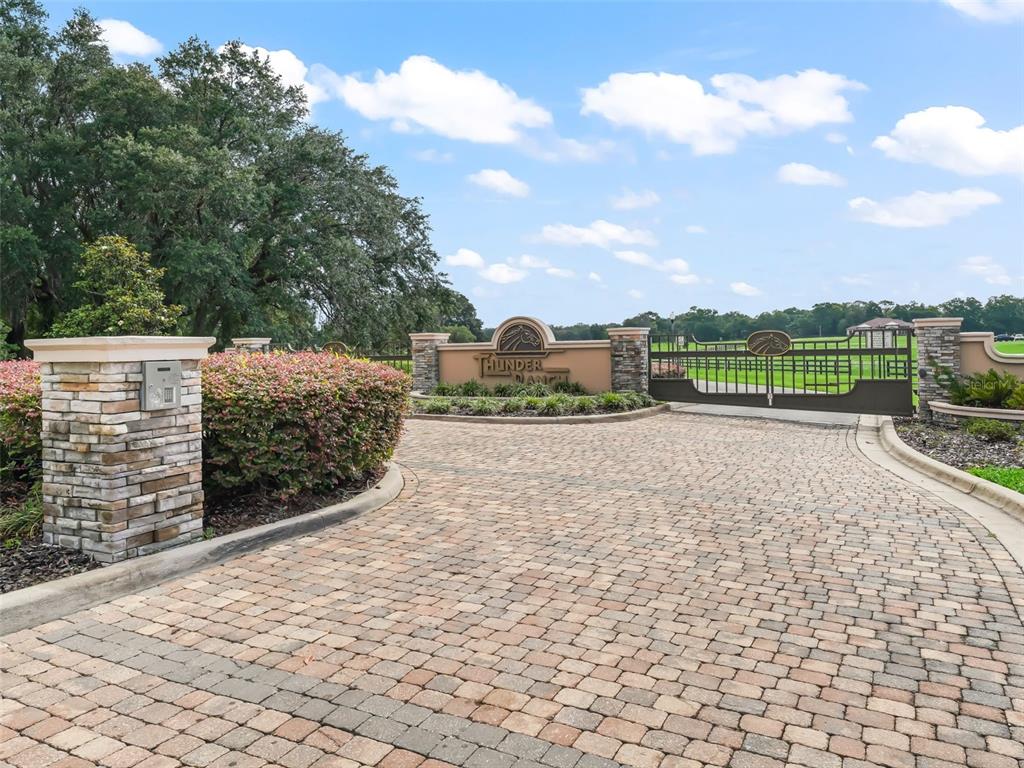 A paved driveway leads to a gated entrance with stone pillars and a ranch sign — 0 NE 54TH TERRACE, ANTHONY, FL