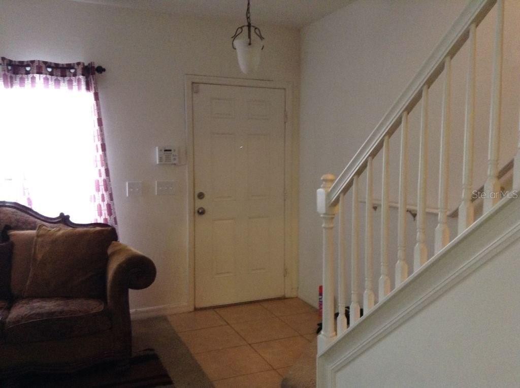 An entryway features a white front door, a staircase with a white railing, and tile flooring — 2310 TRILLIUM PARK LANE, SANFORD, FL