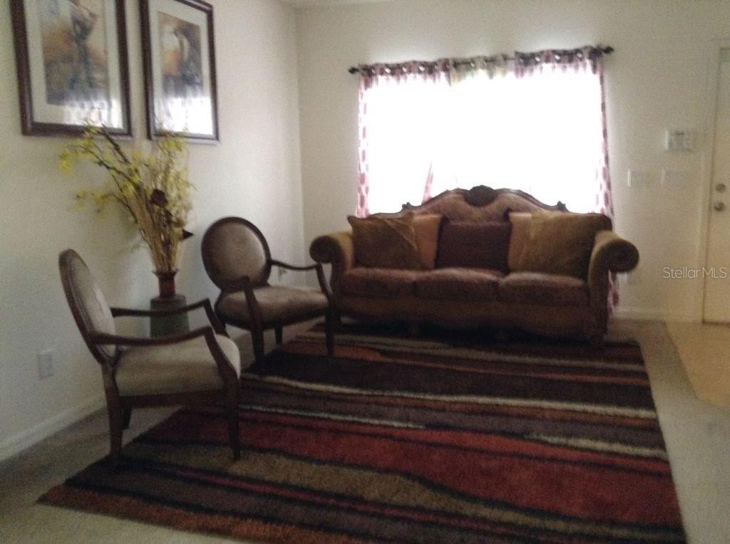A living room features a sofa, two chairs, a patterned rug, and wall art — 2310 TRILLIUM PARK LANE, SANFORD, FL
