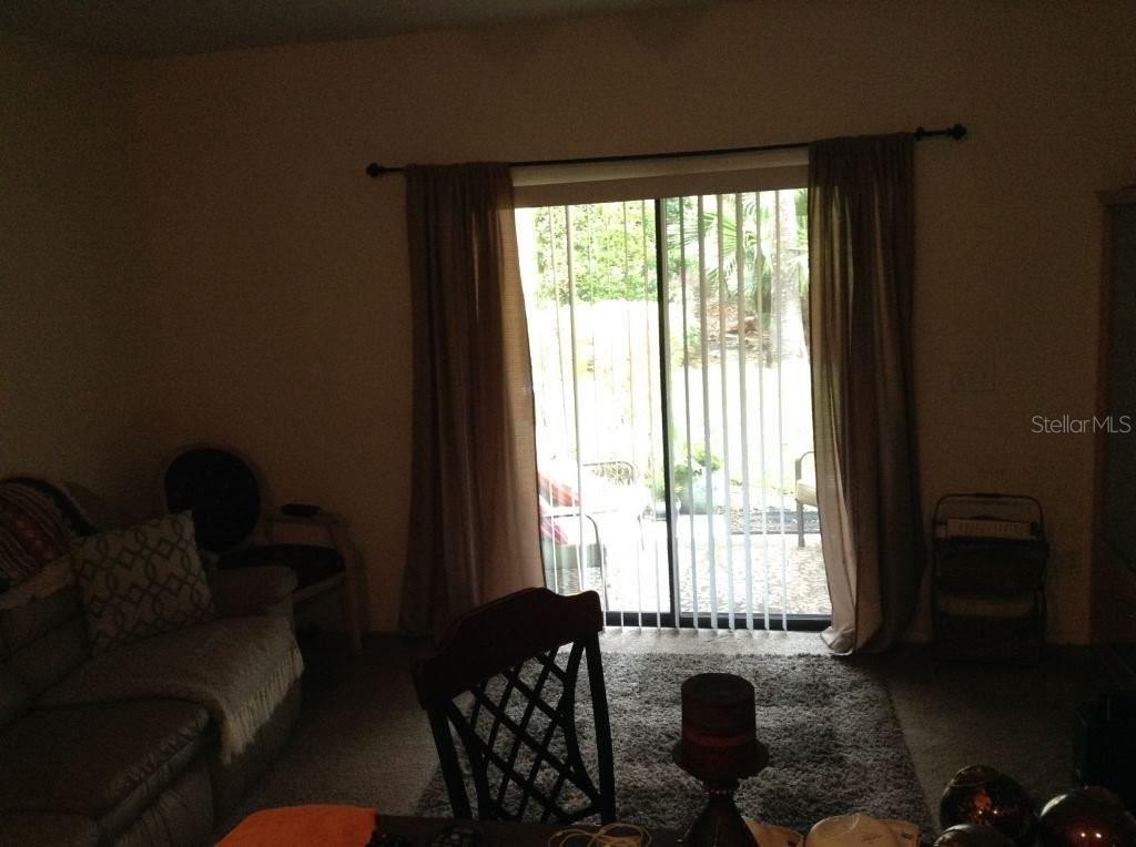 A living room features a sliding glass door with vertical blinds and brown curtains — 2310 TRILLIUM PARK LANE, SANFORD, FL