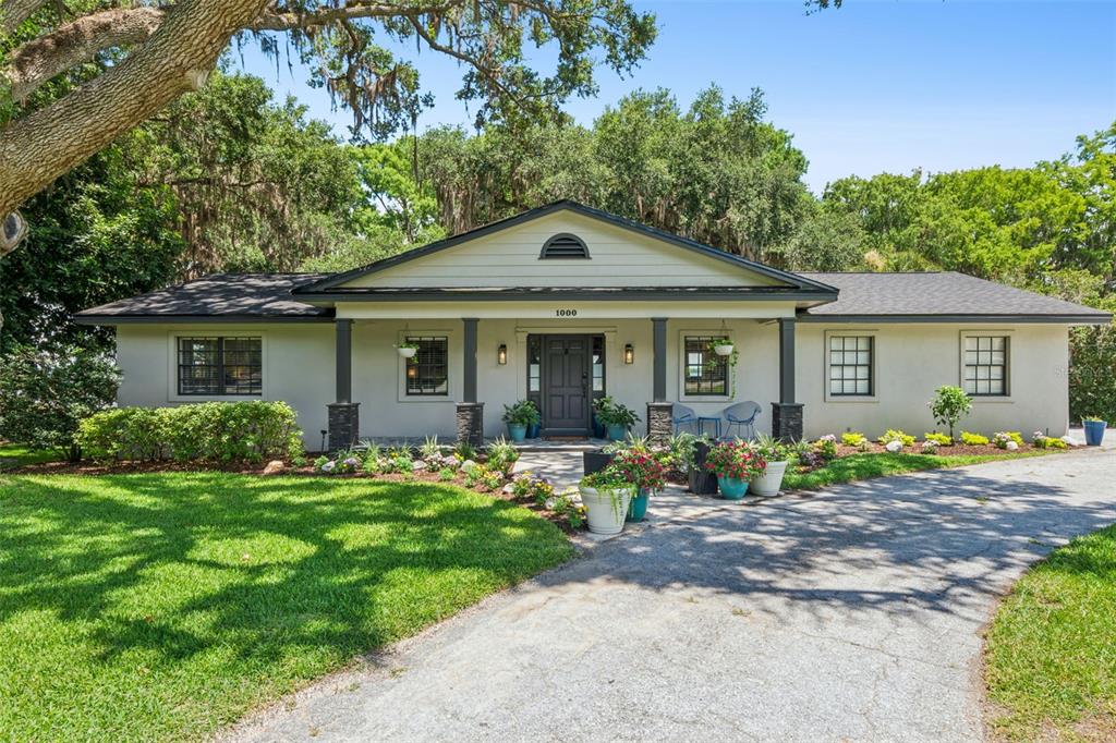 A single-story house with a covered front porch, dark columns, and a paved driveway — 1000 N LAKESHORE BOULEVARD, HOWEY IN THE HILLS, FL
