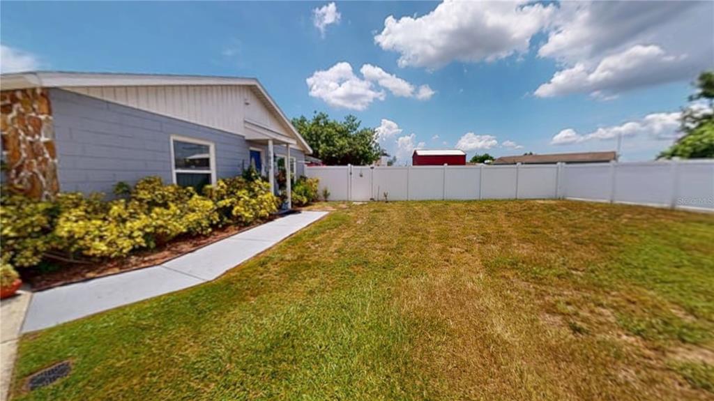 A side view of a house with gray siding, a stone accent wall, and a lawn — 1215 COOLMONT DRIVE, BRANDON, FL