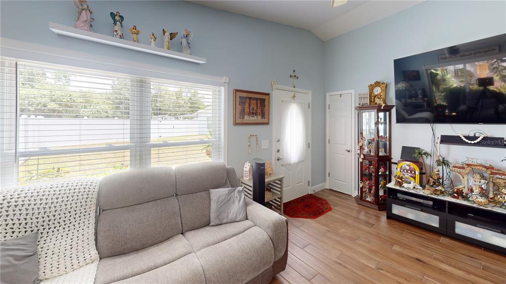 A living room features a light gray sofa, a television, and a glass display cabinet — 1215 COOLMONT DRIVE, BRANDON, FL