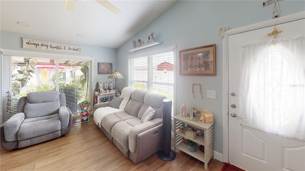 A living room features light blue walls, wood-look flooring, a gray sofa, and a recliner — 1215 COOLMONT DRIVE, BRANDON, FL