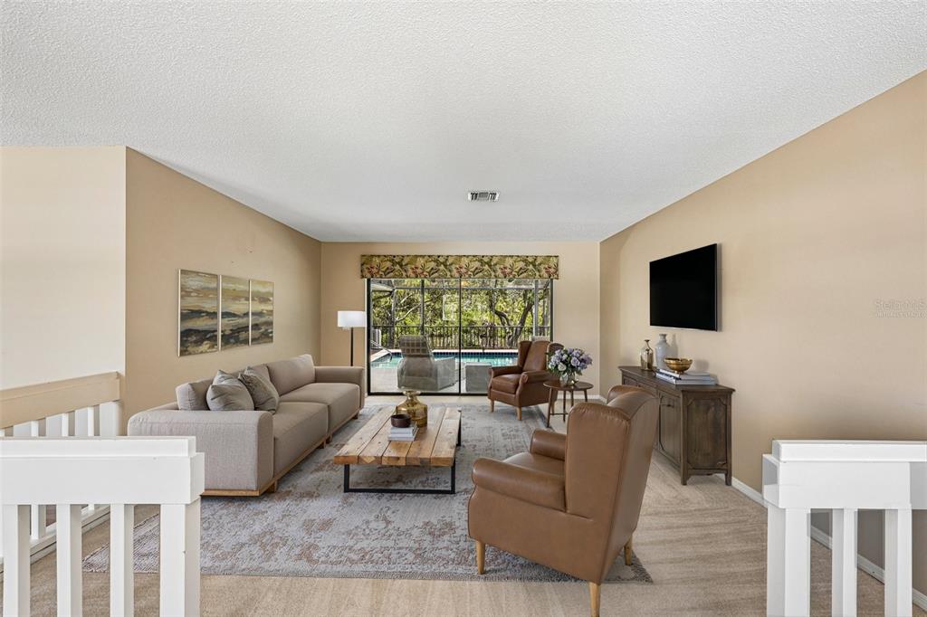 A living room features a beige sofa, two leather armchairs, and a view of a pool — 1305 SORRENTO WOODS BOULEVARD, NOKOMIS, FL