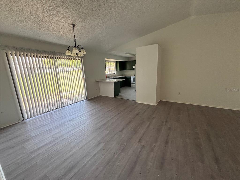A dining area with wood-look flooring and sliding glass doors leads to a kitchen — 1028 HICKORY ROAD, OCALA, FL