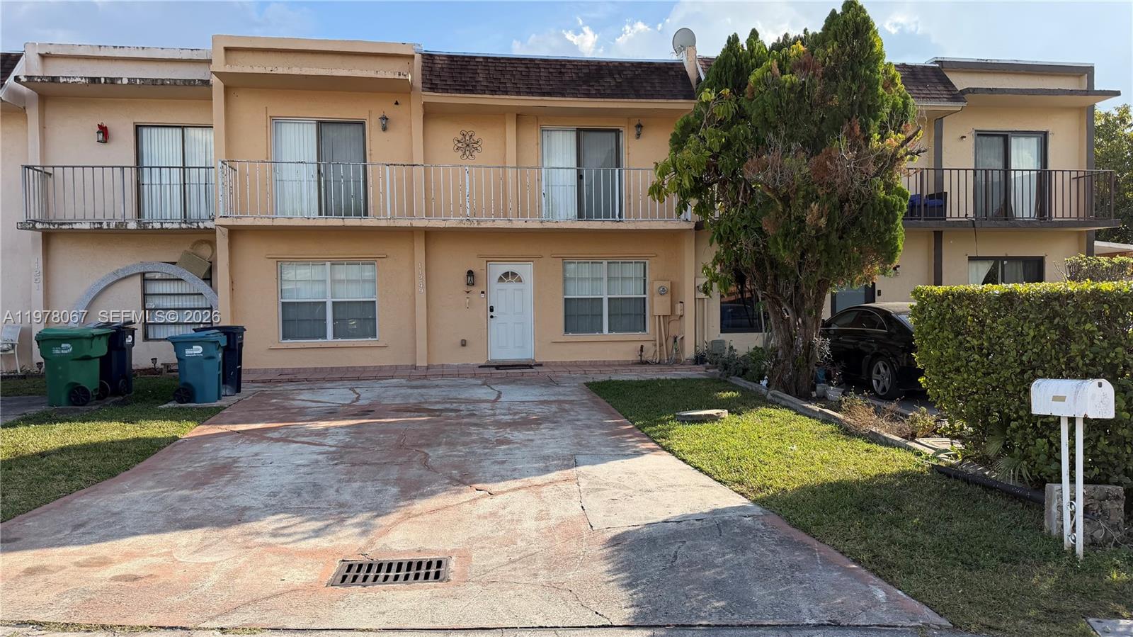 A two-story townhouse features a concrete driveway, a balcony, and a white front door — 11249 SW 33rd Cir Pl, Miami FL 33165, MIAMI, FL