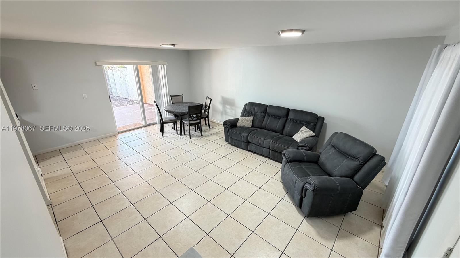 A living room with light tile flooring, a dark sofa, a recliner, and a dining set — 11249 SW 33rd Cir Pl, Miami FL 33165, MIAMI, FL