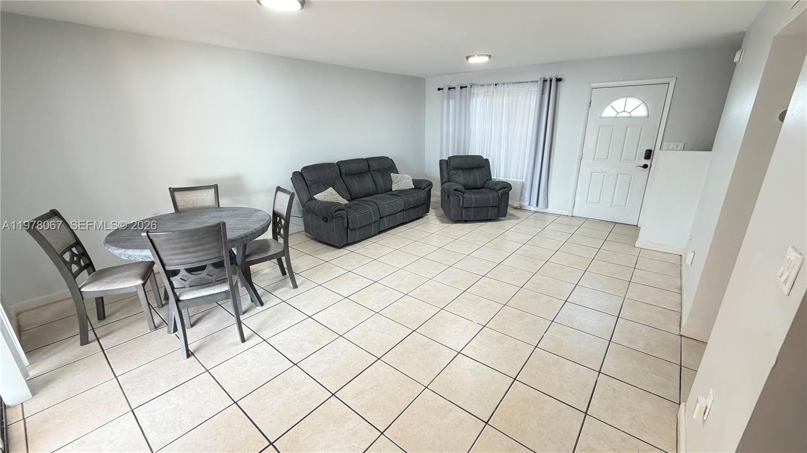 A living and dining area features light tile flooring, gray furniture, and a white door — 11249 SW 33rd Cir Pl, Miami FL 33165, MIAMI, FL