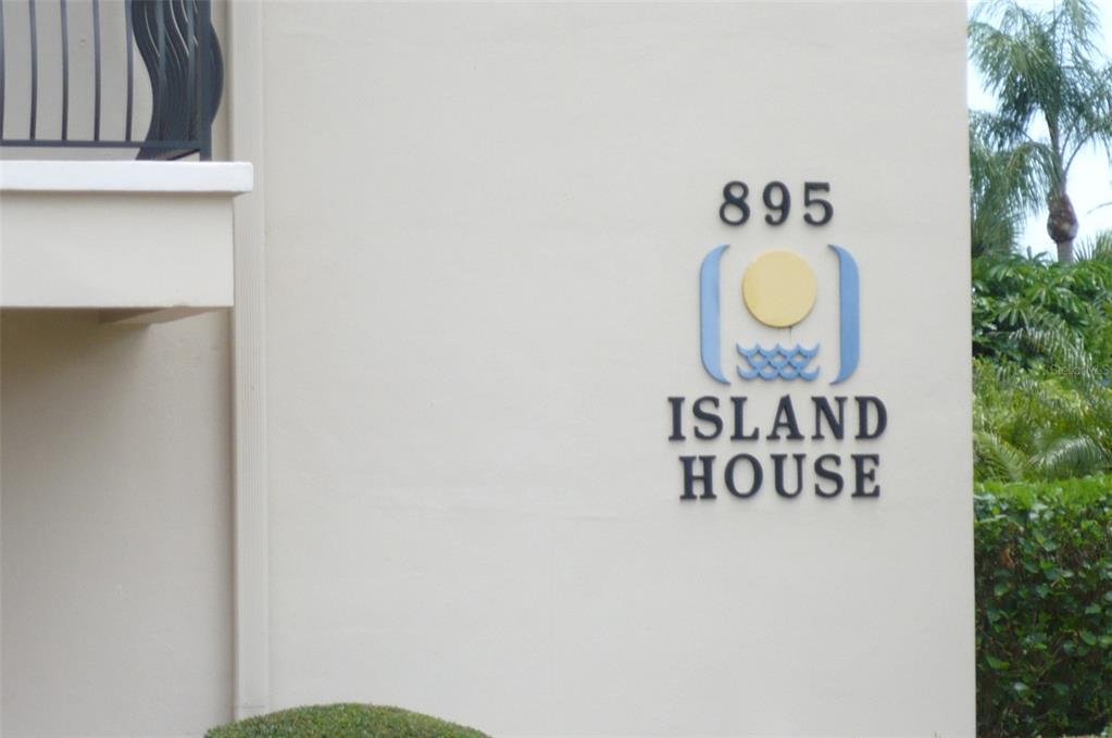 The exterior wall of a building features the address number 895 and an Island House sign — 895 S GULFVIEW BOULEVARD UNIT 203, CLEARWATER BEACH, FL