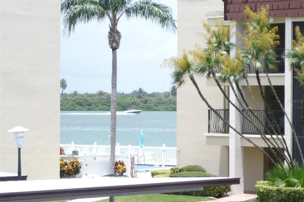A view of a waterway and boat framed by two apartment buildings and palm trees — 895 S GULFVIEW BOULEVARD UNIT 203, CLEARWATER BEACH, FL