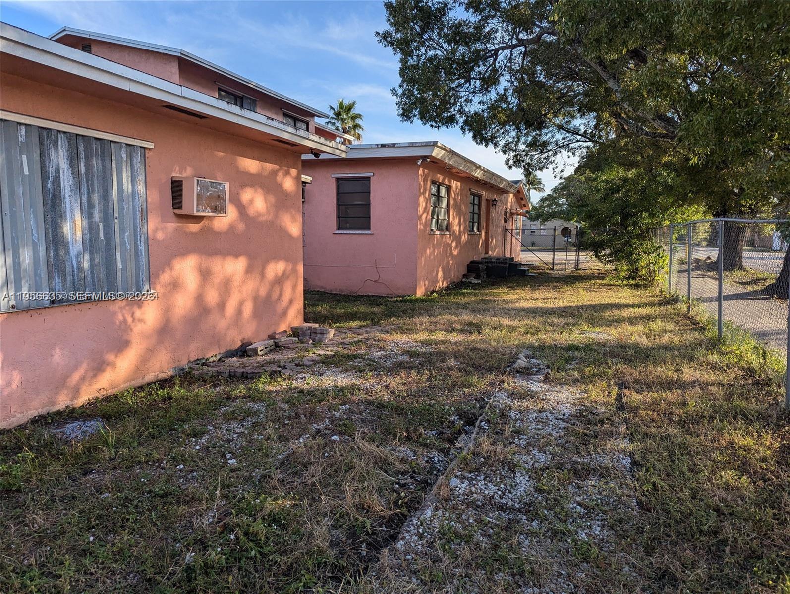 Two pink stucco houses stand on a grassy lot with a chain-link fence — 1853 Taft St, Hollywood FL 33020, HOLLYWOOD, FL
