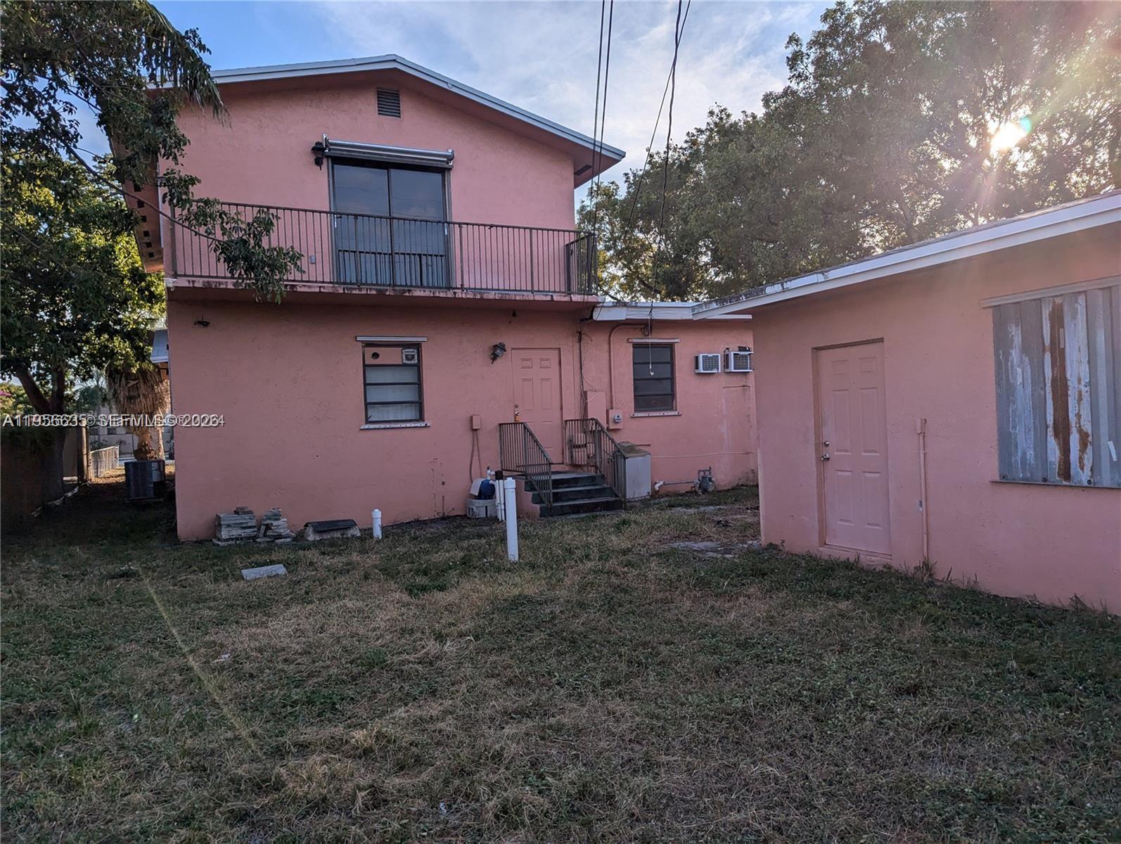 The exterior of a two-story pink house with a balcony and an adjacent detached structure — 1853 Taft St, Hollywood FL 33020, HOLLYWOOD, FL