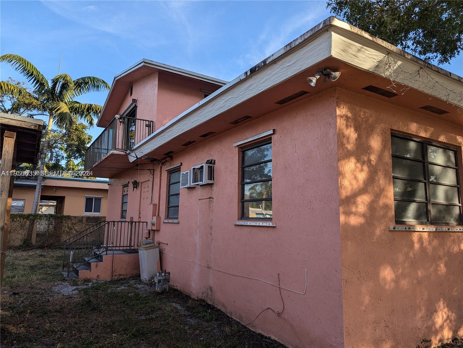 The exterior of a pink stucco house features a second-story balcony and metal-framed windows — 1853 Taft St, Hollywood FL 33020, HOLLYWOOD, FL