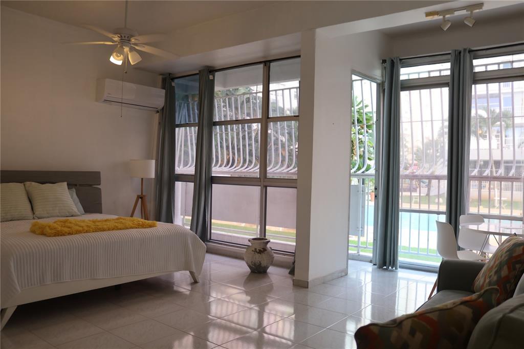 A bedroom with tile floors, a ceiling fan, and large windows overlooking a pool area — 6410 AVE ISLA VERDE UNIT G5, CAROLINA, PR