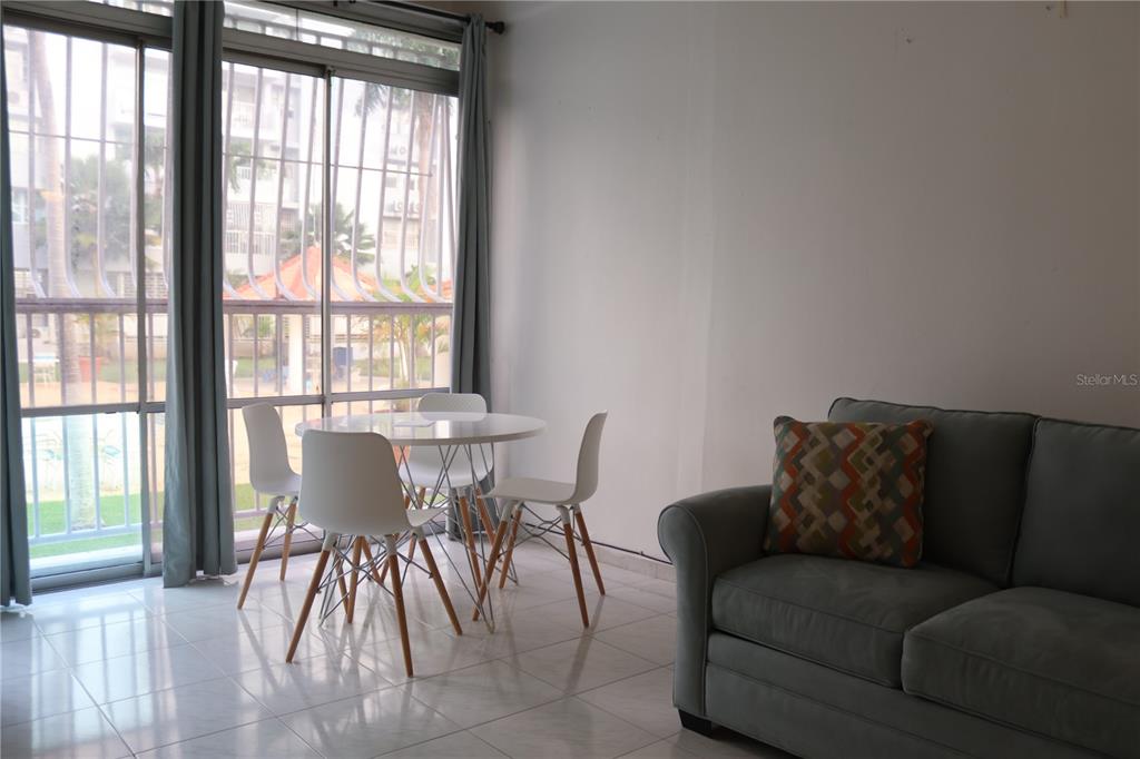 A dining area with a round table and chairs sits beside a sliding glass door — 6410 AVE ISLA VERDE UNIT G5, CAROLINA, PR