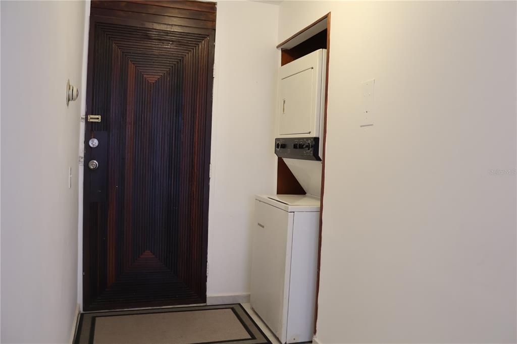 A dark wooden door stands next to a stacked washer and dryer in a hallway — 6410 AVE ISLA VERDE UNIT G5, CAROLINA, PR