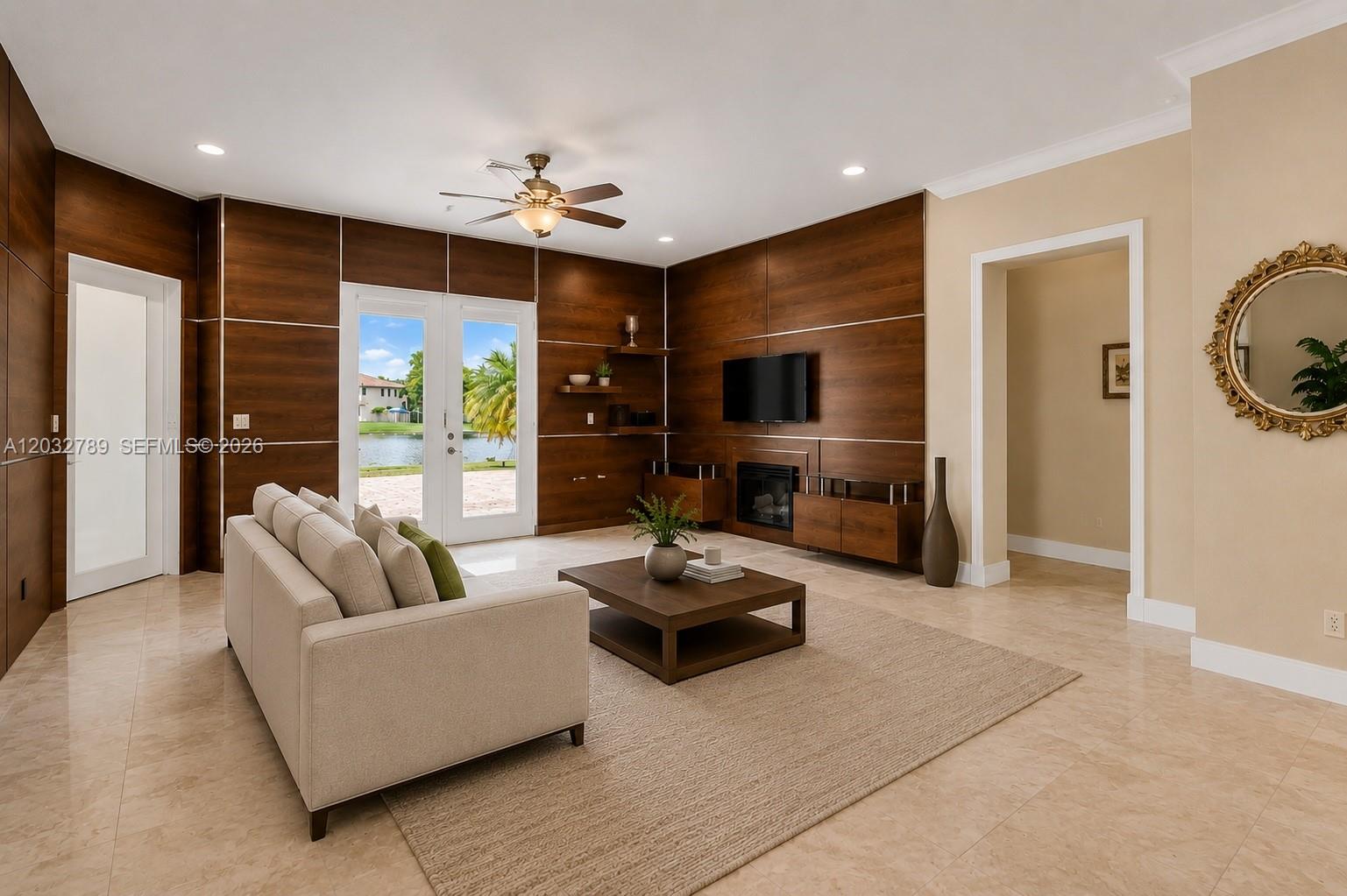 A living room features wood-paneled walls, a fireplace, a television, and a view of water — 19301 Seneca Ave, Weston FL 33332, WESTON, FL