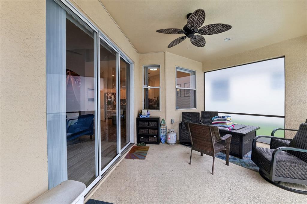 A covered patio features a ceiling fan, sliding glass doors, and outdoor furniture — 304 CALABAY PARC BOULEVARD, DAVENPORT, FL