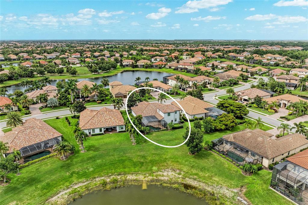 An aerial view shows a two-story house with a screened pool in a suburban neighborhood — 13304 BRIDGEPORT CROSSING, BRADENTON, FL