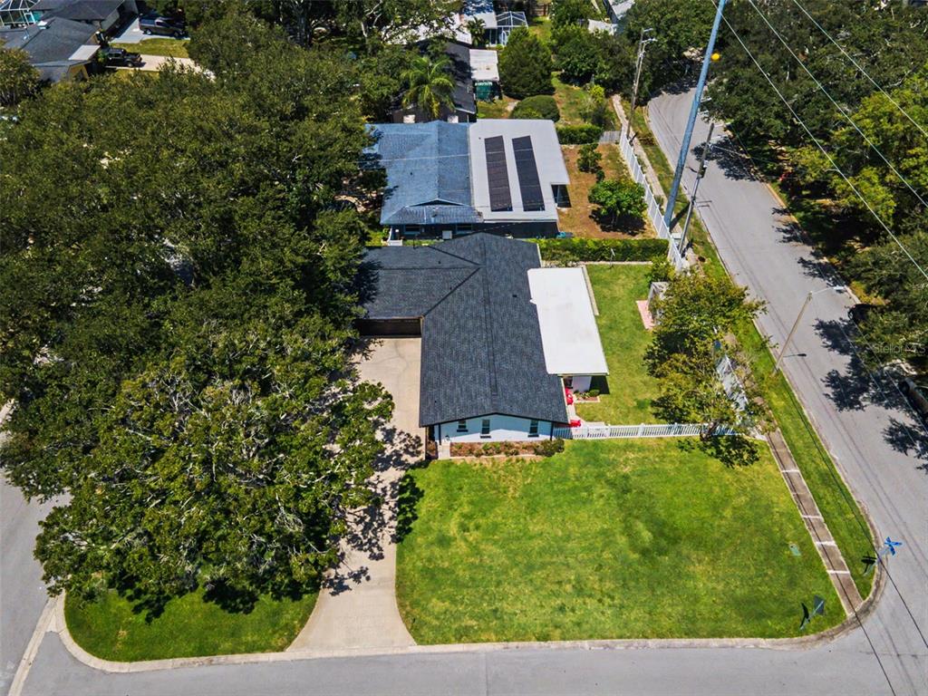 An aerial view shows a single-story house with a dark roof, driveway, and large trees — 1666 SOUVENIR DRIVE, CLEARWATER, FL