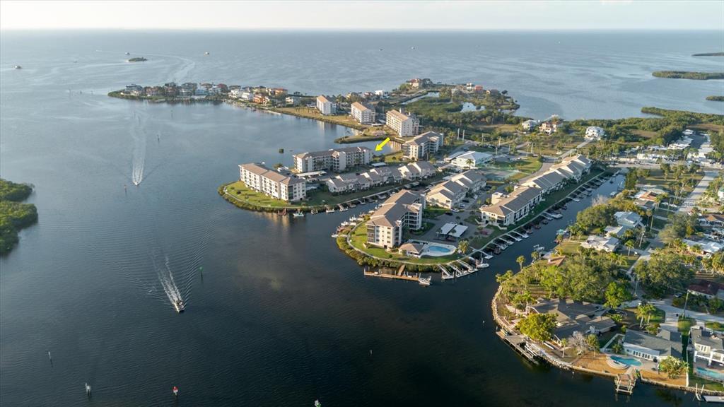 An aerial view shows waterfront condominium buildings with boat slips and a swimming pool — 8211 BRENT STREET UNIT 828, PORT RICHEY, FL
