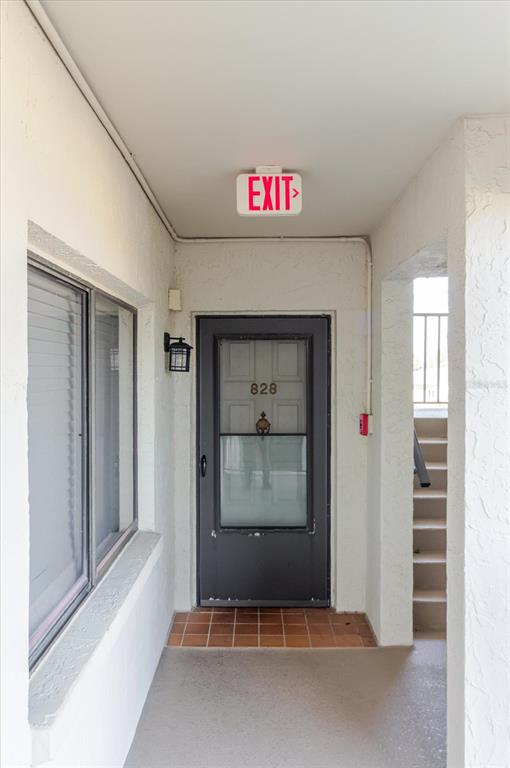 An exterior entryway features a dark door numbered 828, a window, and an exit sign — 8211 BRENT STREET UNIT 828, PORT RICHEY, FL