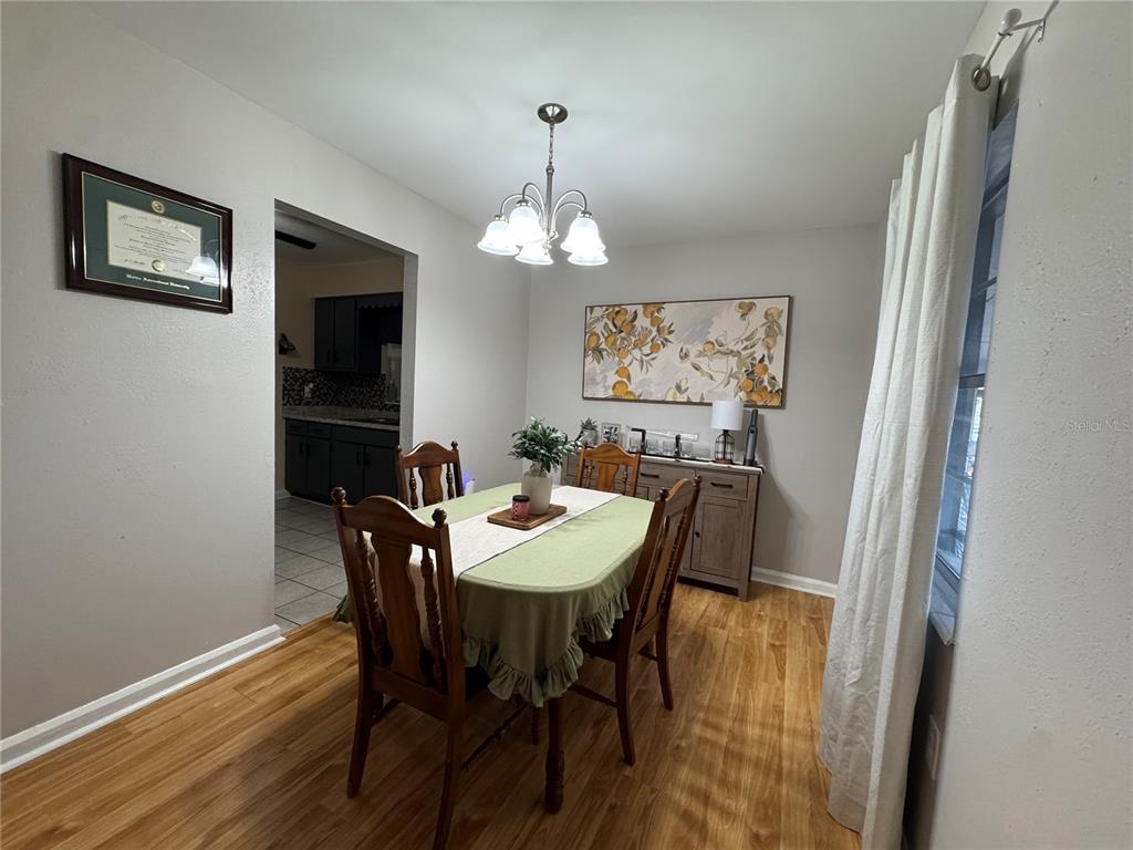 A dining room features a wooden table with chairs, a sideboard, and a light fixture — 519 THOMAS AVENUE, FROSTPROOF, FL