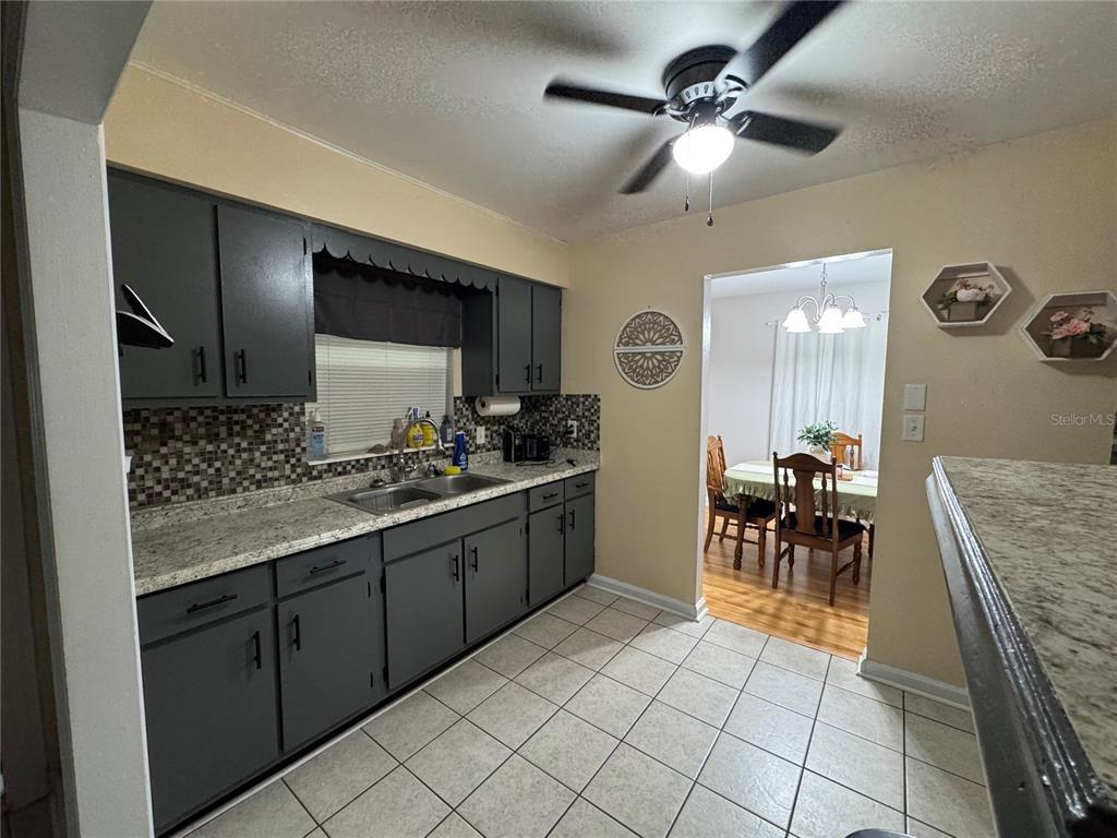 A kitchen features dark gray cabinets, a tiled backsplash, and a granite countertop — 519 THOMAS AVENUE, FROSTPROOF, FL